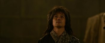 Movie still from “The Man with the Iron Fists” (2012), directed by RZA – A man with long black hair wearing a black robe; Close Up shot, Low angle