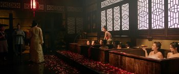 Movie still from “The Man with the Iron Fists” (2012), directed by RZA – A group of people sitting in a bath room with rose petals on the ground; Wide shot, High angle