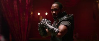 Movie still from “The Man with the Iron Fists” (2012), directed by RZA – A man in a black and white outfit holding something in his hands; Medium shot, Low angle