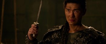 Movie still from “The Man with the Iron Fists” (2012), directed by RZA – A man holding a sword while wearing a leather jacket; Close Up shot, Over the shoulder angle