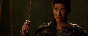Movie still from “The Man with the Iron Fists” (2012), directed by RZA – A man holding a sword in a dark room; Close Up shot, Over the shoulder angle
