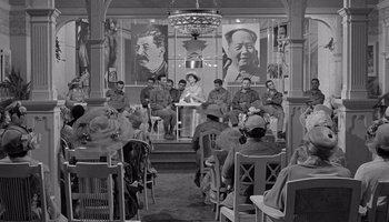 Movie still from “The Manchurian Candidate” (1962), directed by John Frankenheimer – A group of people sitting in chairs in front of a microphone; Wide shot, High angle