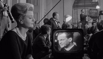 Movie still from “The Manchurian Candidate” (1962), directed by John Frankenheimer – An old photo of a man and a woman watching television; Medium shot, Low angle