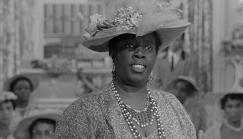 Movie still from “The Manchurian Candidate” (1962), directed by John Frankenheimer – An older black woman wearing a hat and a necklace; Close Up shot, Low angle