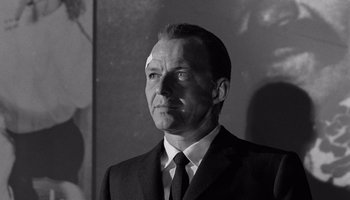 Movie still from “The Manchurian Candidate” (1962), directed by John Frankenheimer – Black and white photograph of a man wearing a suit and tie; Close Up shot, Low angle