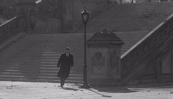 Movie still from “The Manchurian Candidate” (1962), directed by John Frankenheimer – A man walking down a street next to a lamp post; Wide shot, High angle