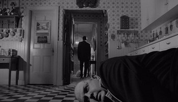 Movie still from “The Manchurian Candidate” (1962), directed by John Frankenheimer – A man standing in a room next to a door; Wide shot, High angle