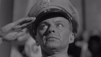 Movie still from “The Manchurian Candidate” (1962), directed by John Frankenheimer – An old black and white photo of a man saluting; Close Up shot, Low angle