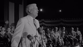 Movie still from “The Manchurian Candidate” (1962), directed by John Frankenheimer – An older man speaking to a crowd of people; Medium shot, Low angle