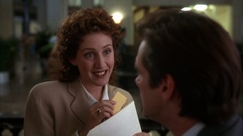 Movie still from “The Mask” (1994), directed by Chuck Russell – A woman holding an envelope and looking at a man; Close Up shot, Over the shoulder angle