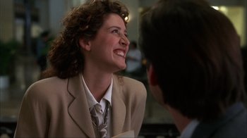 Movie still from “The Mask” (1994), directed by Chuck Russell – A woman wearing a suit and tie smiling at a man in a suit and tie; Close Up shot, Over the shoulder angle