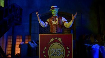 Movie still from “The Mask” (1994), directed by Chuck Russell – A man in a striped vest and hat standing in front of a sign; Medium shot, Over the shoulder angle
