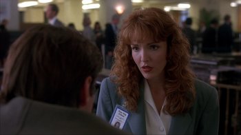 Movie still from “The Mask” (1994), directed by Chuck Russell – A woman in a business suit talking to a man in a business suit; Close Up shot, Over the shoulder angle