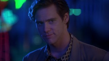 Movie still from “The Mask” (1994), directed by Chuck Russell – A young man with short dark hair wearing a jacket and a tie; Close Up shot, Low angle