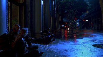 Movie still from “The Mask” (1994), directed by Chuck Russell – A group of people sitting on the sidewalk at night; Wide shot, High angle