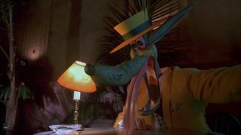 Movie still from “The Mask” (1994), directed by Chuck Russell – A lamp sitting on top of a table next to a plant; Close Up shot, Over the shoulder angle