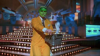 Movie still from “The Mask” (1994), directed by Chuck Russell – A man dressed as the green mask in front of an audience; Medium shot, Low angle