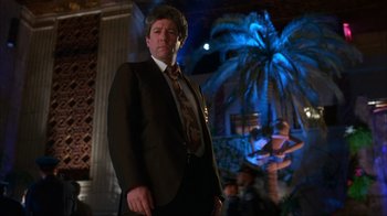 Movie still from “The Mask” (1994), directed by Chuck Russell – A man in a suit standing in front of a palm tree; Medium shot, Low angle