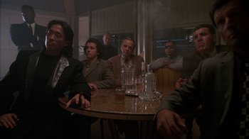 Movie still from “The Mask” (1994), directed by Chuck Russell – A group of men sitting at a table with drinks; Medium shot, Low angle