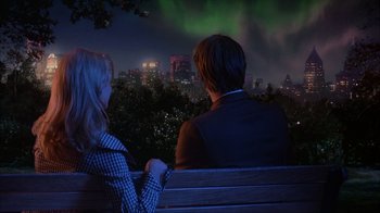 Movie still from “The Mask” (1994), directed by Chuck Russell – A man and a woman sitting on a bench in front of a city skyline at night; Wide shot, Over the shoulder angle