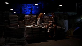 Movie still from “The Mask” (1994), directed by Chuck Russell – A man and a woman sitting on top of a pile of papers; Wide shot, High angle