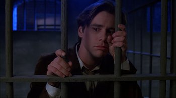 Movie still from “The Mask” (1994), directed by Chuck Russell – A man in a suit looking through a jail cell window; Close Up shot, Low angle