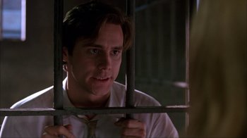 Movie still from “The Mask” (1994), directed by Chuck Russell – A man in a white dress shirt and tie behind bars looking out a window; Close Up shot, Low angle