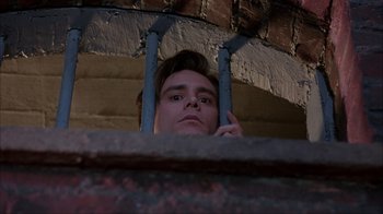 Movie still from “The Mask” (1994), directed by Chuck Russell – A young man looking over a railing at a brick wall; Close Up shot, Low angle