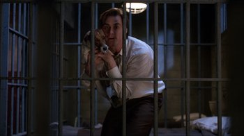 Movie still from “The Mask” (1994), directed by Chuck Russell – A man in a suit and tie holding a dog; Medium shot, Low angle