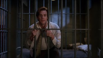 Movie still from “The Mask” (1994), directed by Chuck Russell – A man in a jail cell with his hands on the bars; Medium shot, Low angle