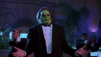 Movie still from “The Mask” (1994), directed by Chuck Russell – A man in a suit and mask standing in front of palm trees at night; Medium shot, Low angle
