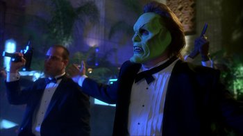 Movie still from “The Mask” (1994), directed by Chuck Russell – A man in a green mask and a man in a black suit; Medium shot, Over the shoulder angle