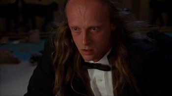 Movie still from “The Mask” (1994), directed by Chuck Russell – A person with long hair wearing a tuxedo; Close Up shot, Low angle