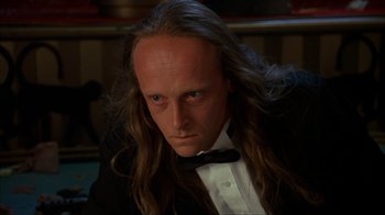 Movie still from “The Mask” (1994), directed by Chuck Russell – A person with long hair wearing a tuxedo; Close Up shot, High angle