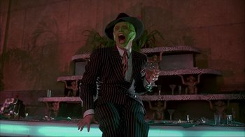 Movie still from “The Mask” (1994), directed by Chuck Russell – A man in a striped suit and a hat holding a glass of wine; Medium shot, Low angle