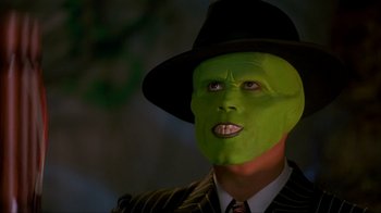 Movie still from “The Mask” (1994), directed by Chuck Russell – A man in a suit and hat with a green mask on his face; Close Up shot, High angle