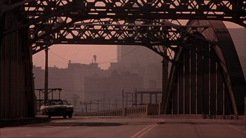 Movie still from “The Mask” (1994), directed by Chuck Russell – A car driving on a street under a bridge; Extreme Wide shot, Low angle