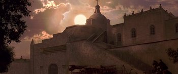 Movie still from “The Mask of Zorro” (1998), directed by Martin Campbell – The sun is setting behind a large building; Extreme Wide shot, Low angle