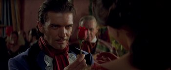 Movie still from “The Mask of Zorro” (1998), directed by Martin Campbell – A man holding a red rose in front of another man; Close Up shot, Over the shoulder angle