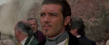 Movie still from “The Mask of Zorro” (1998), directed by Martin Campbell – A person wearing a suit and tie; Close Up shot, Low angle