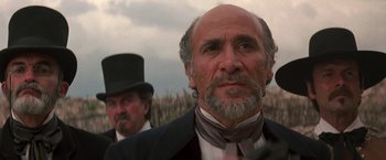 Movie still from “The Mask of Zorro” (1998), directed by Martin Campbell – A man in a top hat and a suit and tie standing next to another man in a top hat and a suit; Close Up shot, Low angle