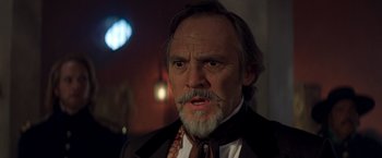 Movie still from “The Mask of Zorro” (1998), directed by Martin Campbell – An old man with a beard and mustache wearing a suit and tie; Close Up shot, Low angle