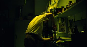 Movie still from “The Master” (2012), directed by Paul Thomas Anderson – A man standing in a room next to a shelf; Medium shot, Low angle