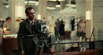 Movie still from “The Master” (2012), directed by Paul Thomas Anderson – A man standing in front of a camera in a room; Medium shot, Over the shoulder angle
