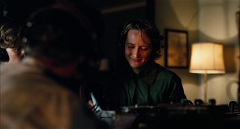 Movie still from “The Master” (2012), directed by Paul Thomas Anderson – A woman wearing headphones looking at her cell phone; Close Up shot, Over the shoulder angle