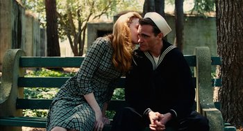 Movie still from “The Master” (2012), directed by Paul Thomas Anderson – A man and a woman sitting on a park bench kissing; Medium shot, Low angle