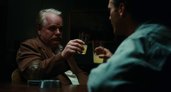 Movie still from “The Master” (2012), directed by Paul Thomas Anderson – Two men sitting at a table with drinks in front of them; Medium shot, Over the shoulder angle