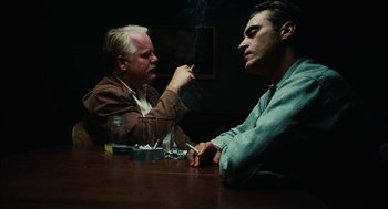 Movie still from “The Master” (2012), directed by Paul Thomas Anderson – Two men sitting at a table smoking cigarettes; Medium shot, Over the shoulder angle