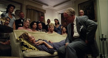 Movie still from “The Master” (2012), directed by Paul Thomas Anderson – An older woman laying on a couch next to a man; Medium shot, Over the shoulder angle