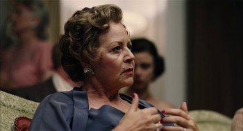 Movie still from “The Master” (2012), directed by Paul Thomas Anderson – An older woman wearing a blue dress is talking to someone; Close Up shot, Over the shoulder angle